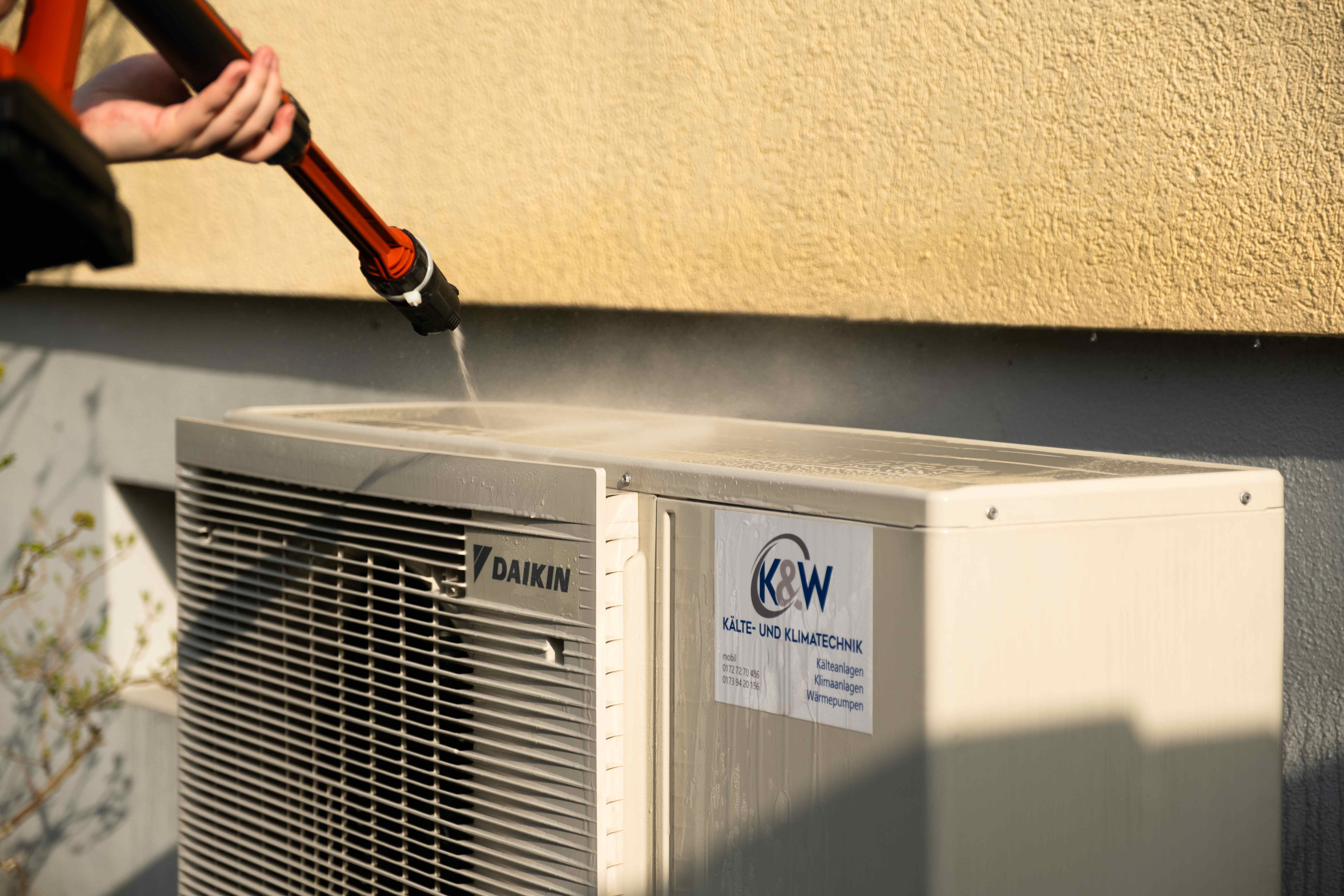 K&W Techniker reinigt Daikin Außengerät mit Hochdruckreiniger