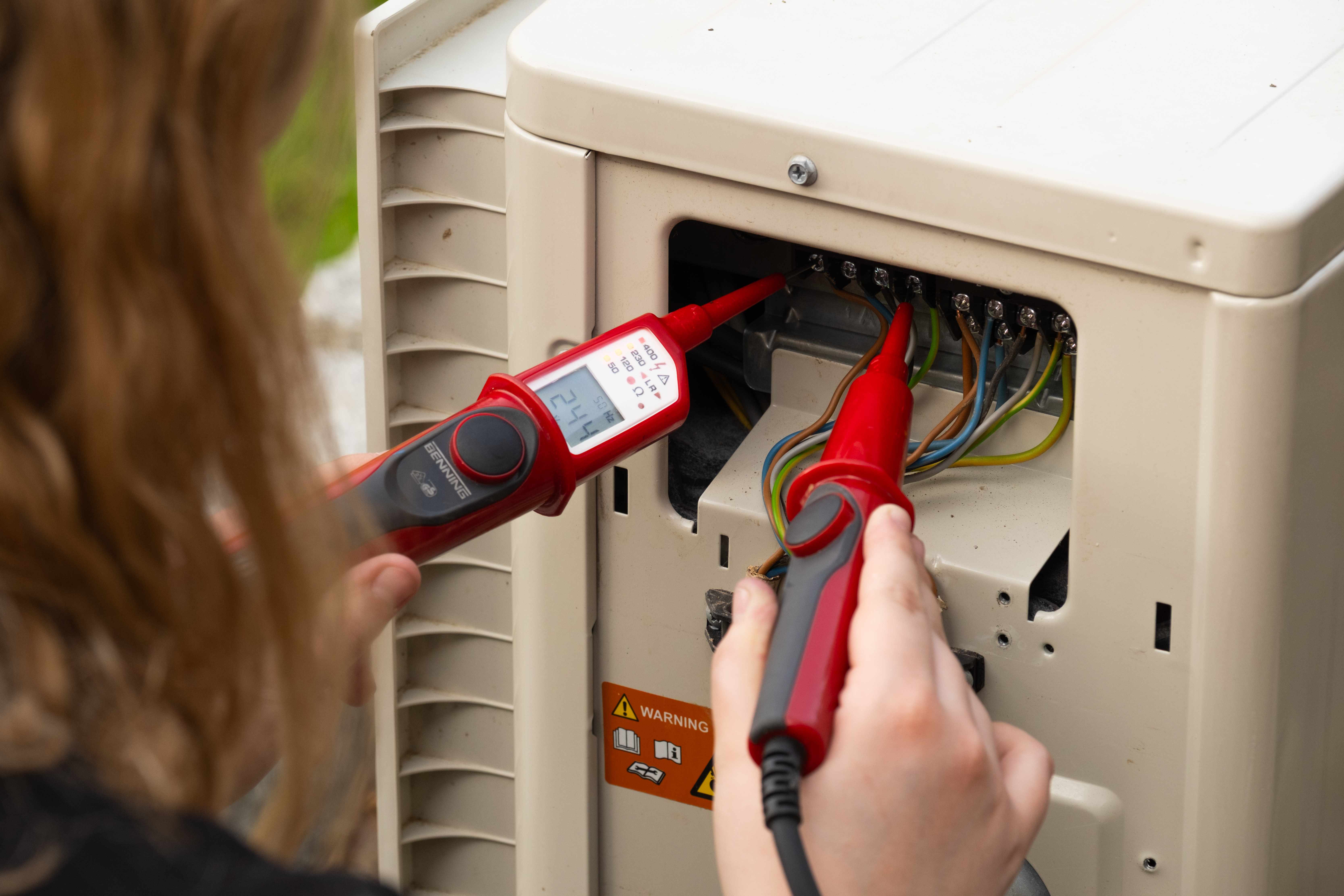K&W Technikerin misst elektrische Spannung an Außengerät